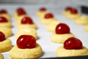 Rows of Sicilian almond cookies with Amarena cherries on top, ready to bake.