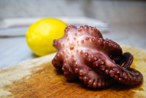 Boiled octopus on a cutting board, with a lemon in the background.