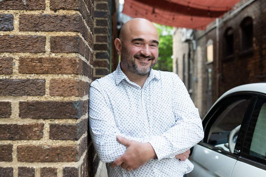 Stefano of Due Spaghetti standing against a brick wall.